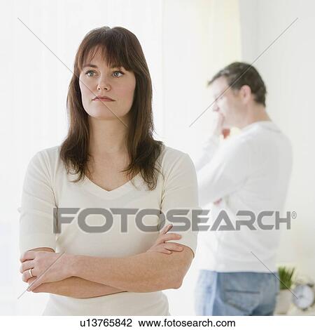 Woman with arms crossed and husband in background View Large Photo Image Stock Image - Woman with arms crossed and husband in background. Fotosearch