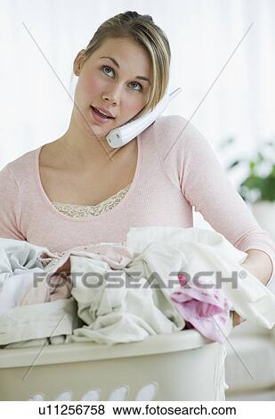 Woman with laundry basket talking on telephone View Large Photo Image Stock Photo - Woman with laundry basket talking on telephone. Fotosearch