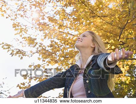Stock Photography - Woman with outstretched arms on a fall day. Fotosearch