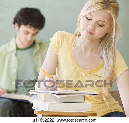 Woman writing at desk in classroom View Large Photo Image Stock Image - Woman writing at desk in classroom. Fotosearch