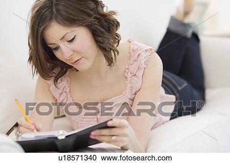 Stock Image - Woman writing in date book. Fotosearch