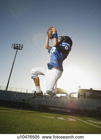 Stock Photography - Young football player catching ball. Fotosearch