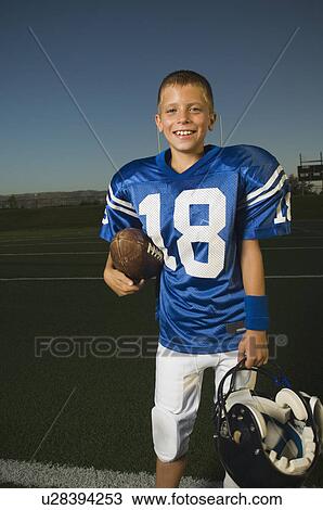 Young football player holding ball and helmet View Large Photo Image Stock Image - Young football player holding ball and helmet. Fotosearch
