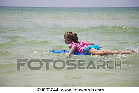 Picture - Young girl floating on boogie board, Florida, United States. Fotosearch