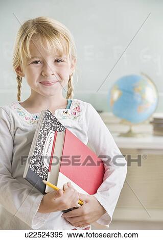 Stock Photography - Young girl holding school books and smiling. Fotosearch