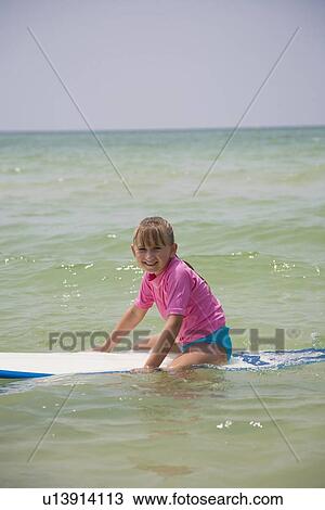 Stock Image - Young girl sitting on boogie board, Florida, United States. Fotosearch