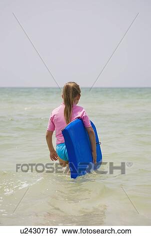 Young girl walking into water with boogie board, Florida, United States View Large Photo Image Stock Photo - Young girl walking into water with boogie board, Florida, United States. Fotosearch