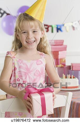 Young girl wearing party hat and holding gift View Large Photo Image Stock Image - Young girl wearing party hat and holding gift. Fotosearch