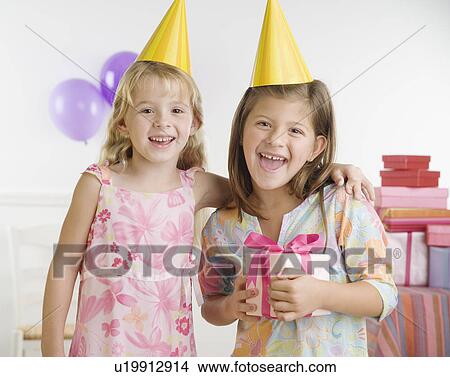 Young sisters wearing party hats and holding gift View Large Photo Image Picture - Young sisters wearing party hats and holding gift. Fotosearch