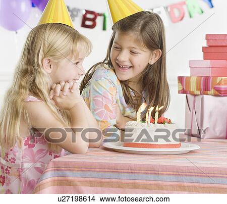 Picture - Young sisters with birthday cake at table. Fotosearch