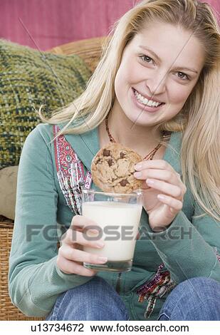 Young woman enjoying a cookie and milk View Large Photo Image Stock Image - Young woman enjoying a cookie and milk. Fotosearch