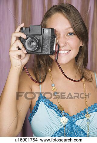 Young woman holding camera up to face View Large Photo Image Picture - Young woman holding camera up to face. Fotosearch
