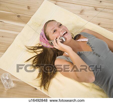Young woman laying on floor using cell phone View Large Photo Image Stock Photo - Young woman laying on floor using cell phone. Fotosearch