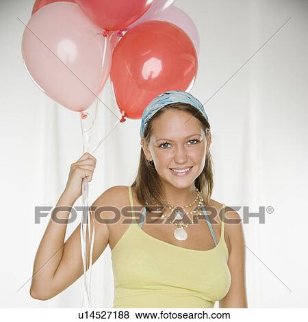 Stock Photo - Young woman smiling and holding bunch of balloons. Fotosearch