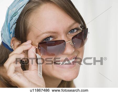 Young woman smiling and trying on sunglasses View Large Photo Image Stock Photograph - Young woman smiling and trying on sunglasses. Fotosearch