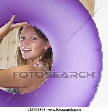 Young woman smiling through middle of inner tube View Large Photo Image Stock Image - Young woman smiling through middle of inner tube. Fotosearch