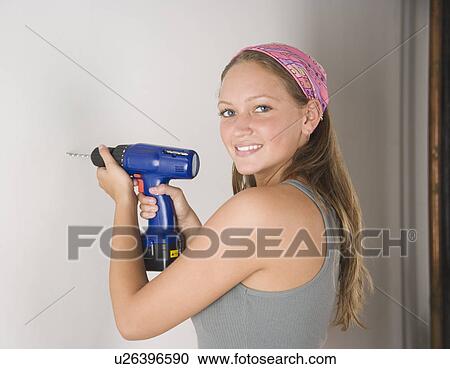 Young woman using cordless drill on wall View Large Photo Image Stock Image - Young woman using cordless drill on wall. Fotosearch