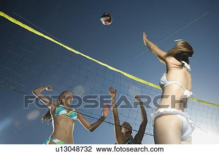 Stock Image - Young women playing beach volleyball. Fotosearch