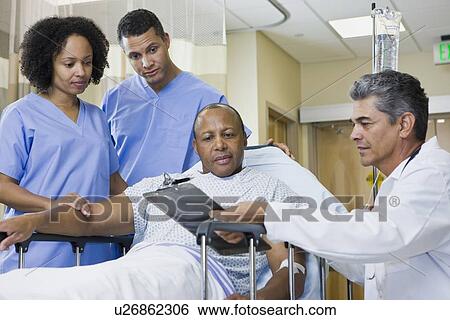 Stock Photograph - African man in hospital gurney looking at clipboard. Fotosearch
