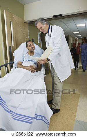 Stock Image - African man in hospital gurney reading paperwork. Fotosearch
