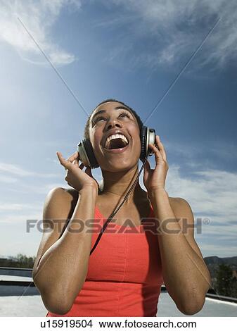 Picture - African woman listening to headphones. Fotosearch