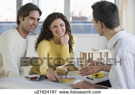 Stock Photo - Architect presenting plans to couple. Fotosearch