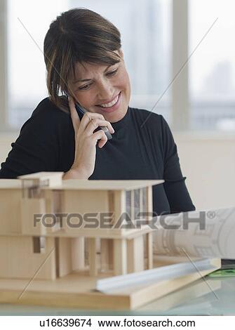 Picture - Architect talking on cell phone next to building model. Fotosearch