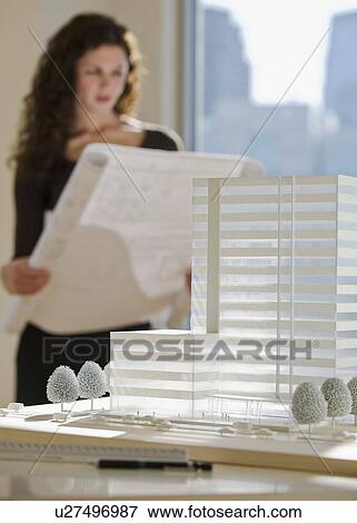Stock Photo - Architect viewing blueprints near building model. Fotosearch