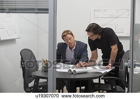 Stock Image - Architects reviewing blueprints. Fotosearch