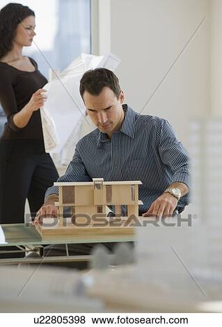 Stock Photo - Architects working with blueprints and building model. Fotosearch