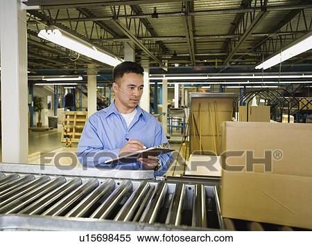 Stock Photography - Asian male factory worker checking product. Fotosearch