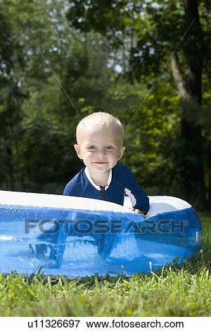 Stock Photo - Baby boy playing in inflatable swimming pool. Fotosearch