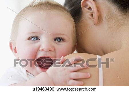 Baby laughing over mother’s shoulder View Large Photo Image Stock Photograph - Baby laughing over mother’s shoulder. Fotosearch