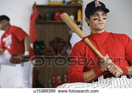 Baseball player holding bat in locker room View Large Photo Image Stock Photo - Baseball player holding bat in locker room. Fotosearch