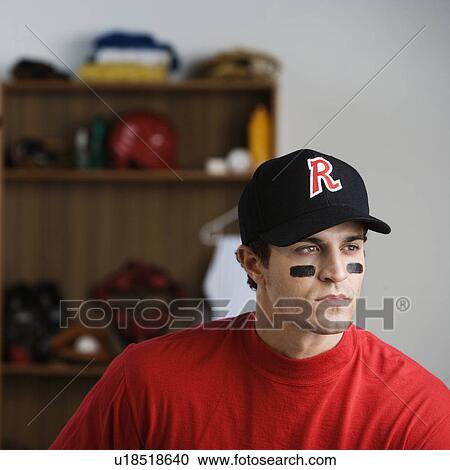 Stock Image - Baseball player looking pensive in locker room. Fotosearch