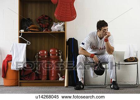Stock Photography - Baseball player sitting in locker room looking pensive. Fotosearch