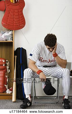 Baseball player sitting with head in hands in locker room View Large Photo Image Picture - Baseball player sitting with head in hands in locker room. Fotosearch