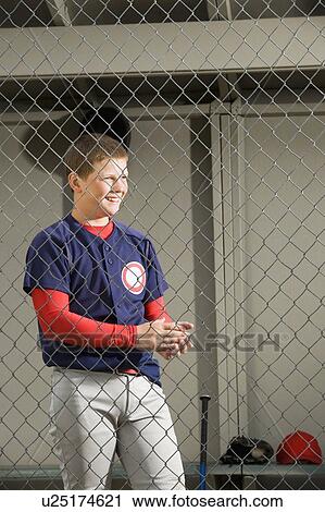 Stock Image - Baseball player standing in dugout. Fotosearch