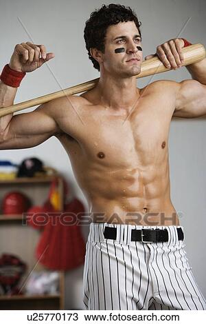 Stock Image - Baseball player with bare chest posing in locker room. Fotosearch