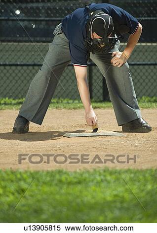 Stock Photography - Baseball umpire sweeping home plate. Fotosearch