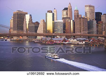 Stock Image - Boat passing under Brooklyn Bridge. Fotosearch