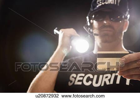 Stock Image - Bouncer checking identification with flashlight. Fotosearch