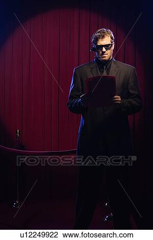 Stock Image - Bouncer looking at guest list. Fotosearch
