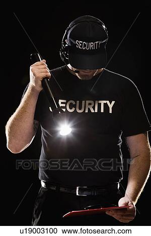 Stock Image - Bouncer looking at guest list with flashlight. Fotosearch