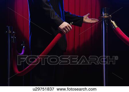 Stock Photo - Bouncer unhooking velvet rope. Fotosearch