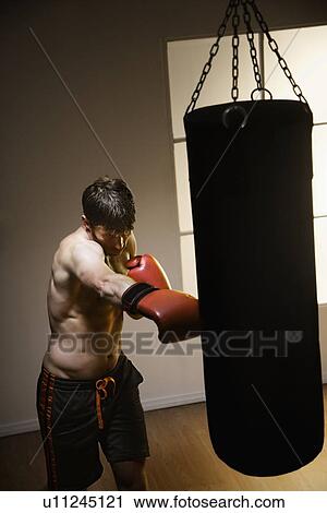 Stock Image - Boxer training with punching bag. Fotosearch