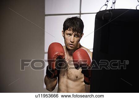 Stock Photograph - Boxer training with punching bag. Fotosearch