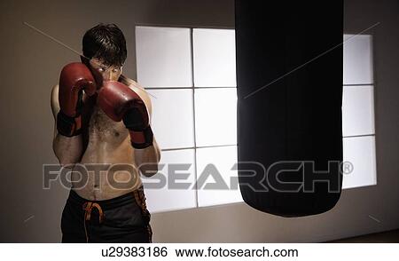 Stock Photograph - Boxer training with punching bag. Fotosearch