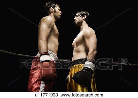 Stock Image - Boxers facing off in boxing ring. Fotosearch