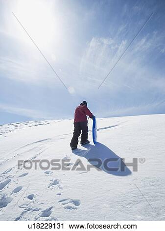 Stock Image - Boy carrying sled in snow. Fotosearch
